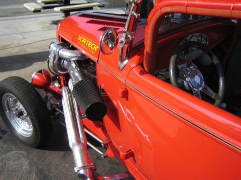 1985 Ford Mustang - A bright red hot rod is shown from the side, custom engine components and interior details.