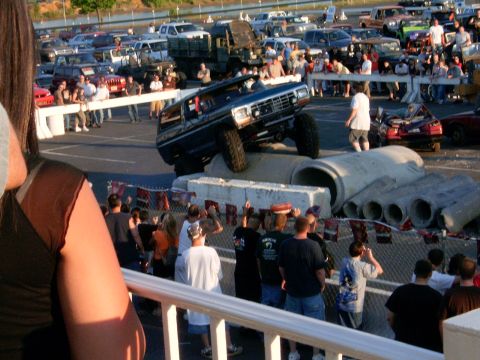 1986 Ford F-250 - A heavily modified Ford Bronco navigates a challenging obstacle course in front of a crowd.