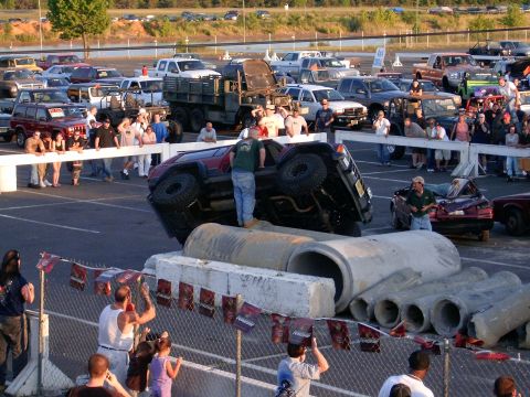 1986 Ford F-250 - A crowd watches as an off-road vehicle is positioned on large concrete pipes.