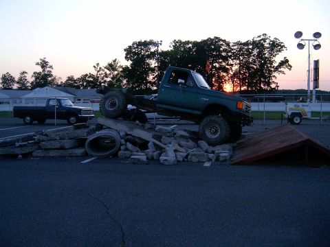 1986 Ford F-250 - Green pickup truck navigating an obstacle course at sunset, with another truck visible.