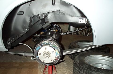 1968 Chevrolet Camaro - The rear suspension of a 1968 Chevrolet Camaro is visible, showing the axle, leaf springs, and brake components during restoration.