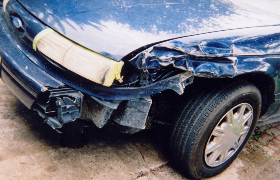 1993 Ford Taurus front fender and bumper damaged from collision. Headlight taped
