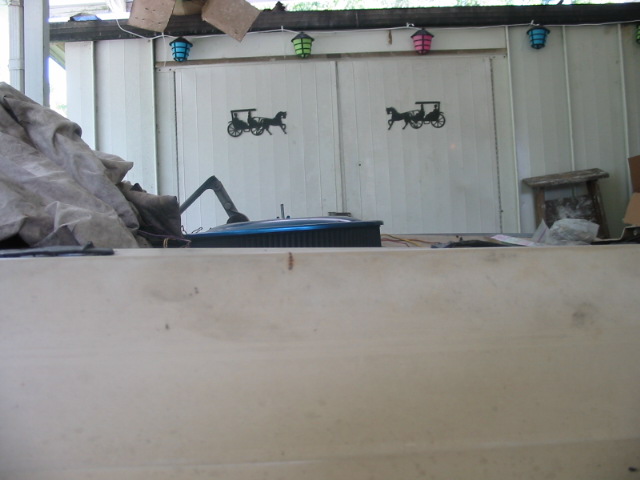 Car hood and engine components under a tarp, viewed from above