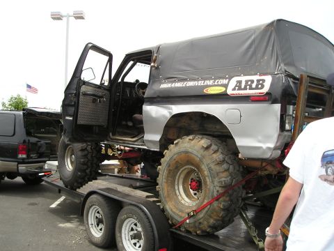 1996 Ford Bronco - A heavily modified truck with a soft top is loaded onto a trailer, with another vehicle visible in the background.