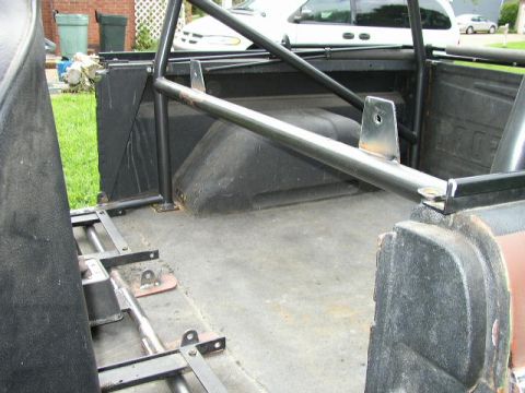 1995 Ford Bronco - The interior of a vehicle shows a roll cage and custom seat mounting hardware.