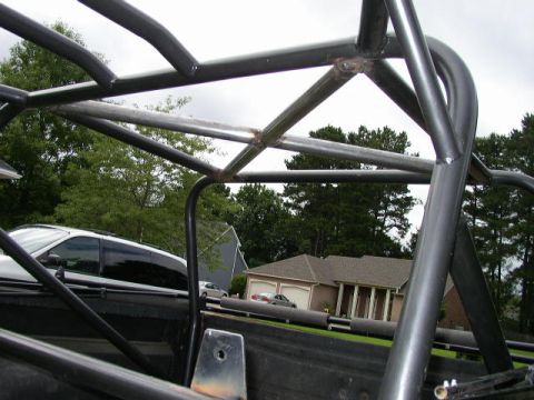1995 Ford Bronco - Custom roll cage tubing is installed in the bed of a truck, with a residential house and trees behind.