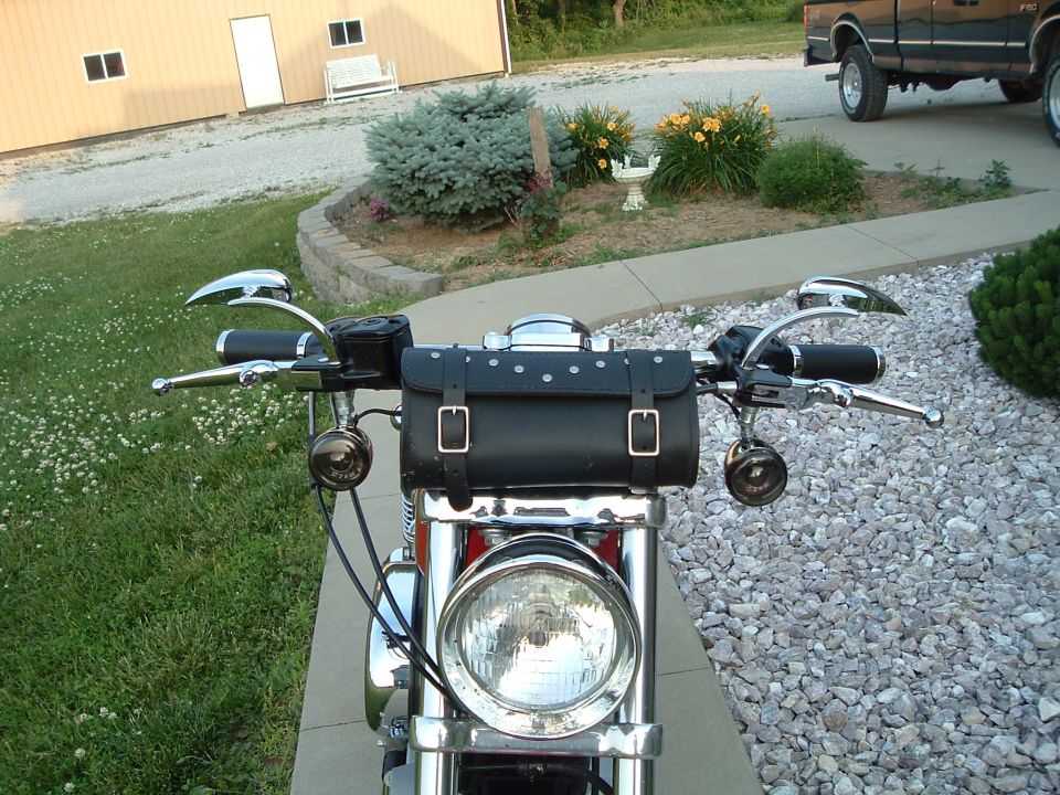 Motorcycle handlebars with chrome mirrors, leather tool bag, and headlight