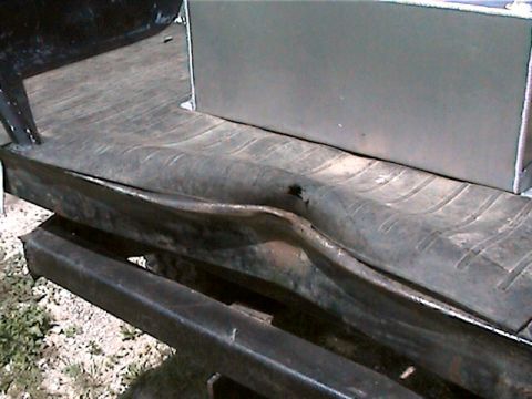 1977 Ford F-150 - The rear of a truck shows a damaged bed floor and a large metal tank mounted above it.