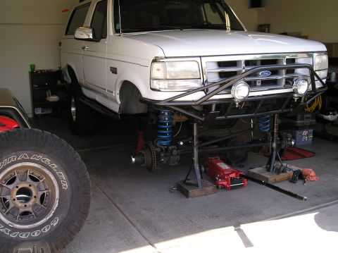 1993 Ford Bronco - White 1993 Ford Bronco undergoing suspension work with a custom front bumper installed.