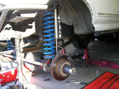 1993 Ford Bronco - Close-up of a vehicle's front suspension system, showing the axle, springs, and shock absorber.