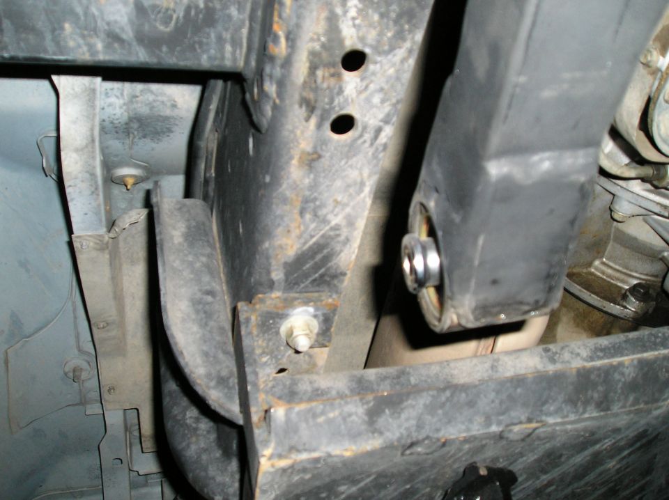 Underside of vehicle frame with rubber body mount bushing and metal sleeve
