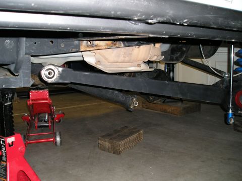 1993 Ford Bronco - Underbody view of a 1993 Ford Bronco, highlighting the extended radius arms and a red hydraulic jack.