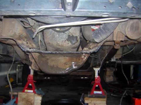1995 Ford Bronco - Vehicle's undercarriage components are visible while it is raised on jack stands for maintenance.