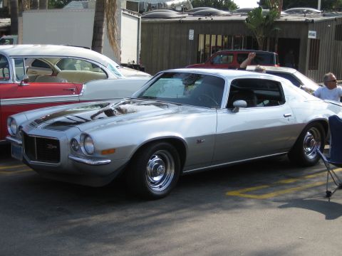 1985 Ford Mustang - A silver 1970 Chevrolet Camaro Z28 is parked next to other classic cars.