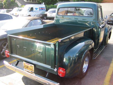 1985 Ford Mustang - A classic green Ford pickup truck is viewed from the rear, parked in a lot.