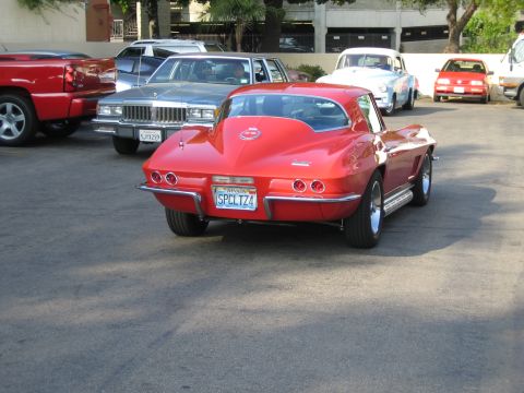 1985 Ford Mustang - A red classic sports car is parked in a lot with other vehicles visible in the background.