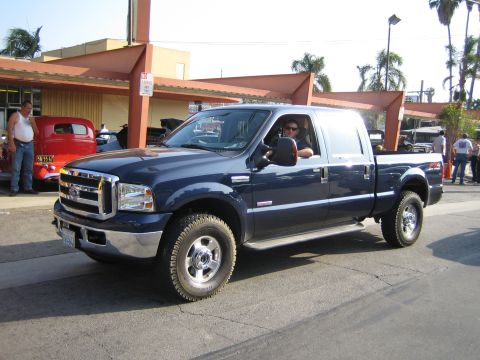 1985 Ford Mustang - A dark blue Ford F-Series truck is seen from the front-three-quarter angle, with a license plate visible on the front bumper.