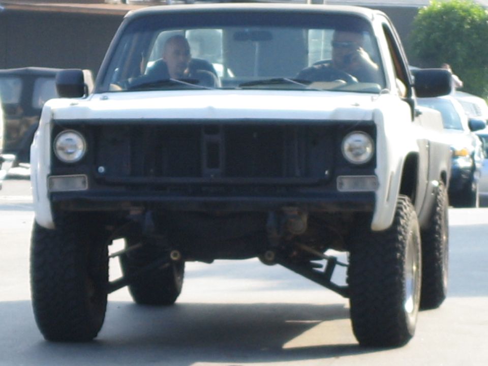 White pickup truck with lifted suspension and off-road tires, front view