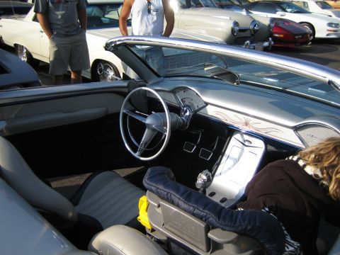 1985 Ford Mustang - Interior of a classic convertible with a child in the passenger seat, parked outdoors.