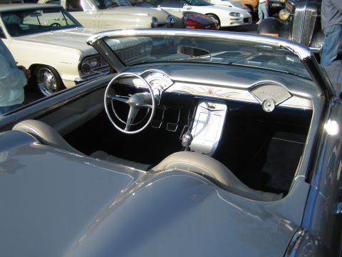 1985 Ford Mustang - The interior of a vintage convertible is shown, with other vehicles parked nearby.
