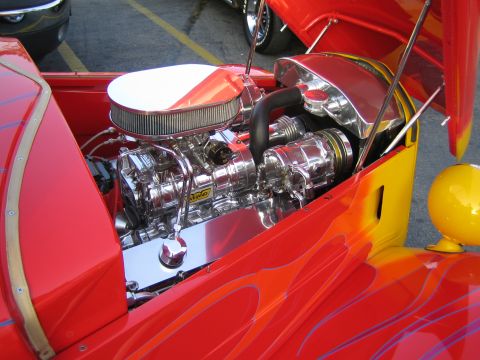 1985 Ford Mustang - The highly polished engine bay of a custom hot rod features a prominent supercharger and flame graphics on the body.