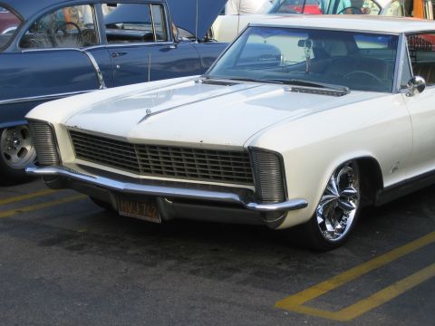 1985 Ford Mustang - White 1965 Buick Riviera parked next to a blue classic car.
