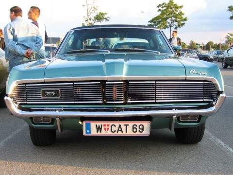 1992 Ford Crown Victoria - A teal Mercury Cougar is parked outside, with people standing nearby.