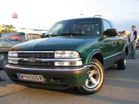 1992 Ford Crown Victoria - A green Chevrolet S-10 pickup truck is parked next to another vehicle, with people standing nearby.