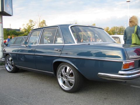 1992 Ford Crown Victoria - A blue sedan with chrome wheels is parked on the street, with a person in the background.