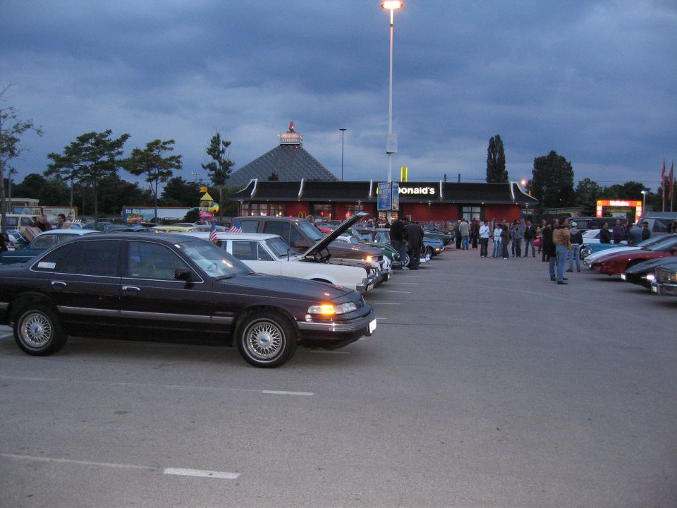 Dark sedan parked in a lot with other cars, McDonald's in background