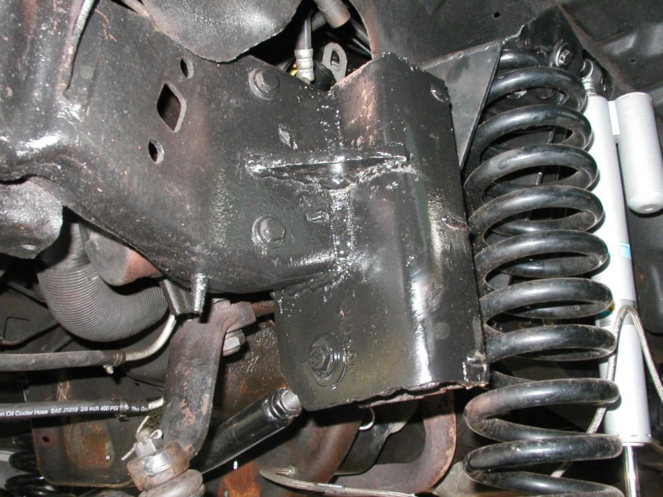 Black painted frame section with visible welds and a large coil spring. A shock absorber is also visible