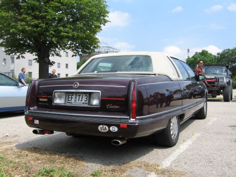 1992 Ford Crown Victoria - A dark purple Cadillac sedan with a white vinyl roof is seen from the rear, parked next to another vehicle.