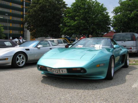 1992 Ford Crown Victoria - A teal sports car is parked next to a silver sports car and a silver SUV at an outdoor event.