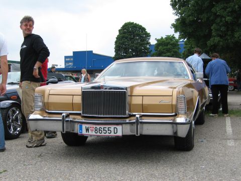 1992 Ford Crown Victoria - A man stands next to a gold Lincoln Continental Mark V at an outdoor car show.