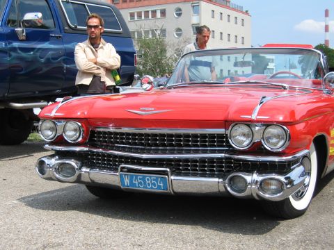 1992 Ford Crown Victoria - A red convertible is parked next to a blue SUV, with two men standing nearby.