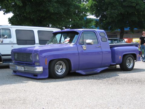 1992 Ford Crown Victoria - This custom pickup truck features a lowered stance, custom grille, and a visor, parked next to a white van.