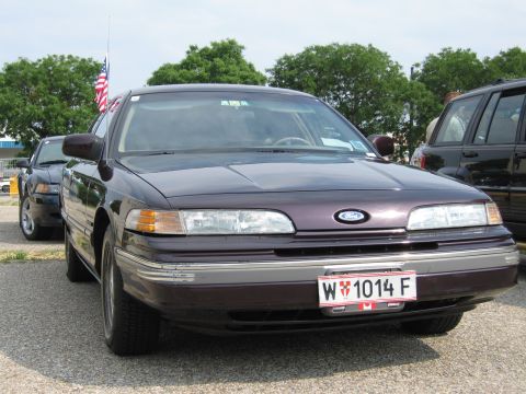 1992 Ford Crown Victoria - A 1992 Ford Crown Victoria is seen from the front, parked next to another vehicle under a cloudy sky.