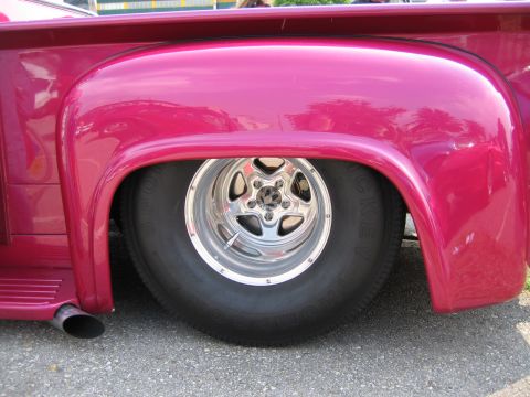 1992 Ford Crown Victoria - Close-up of a custom pink pickup truck's rear wheel and fender assembly.