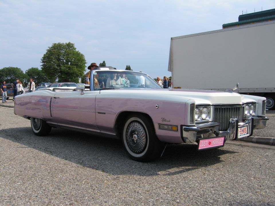 Pink and white convertible with wire wheels and a 'Just Married' sign on the bumper