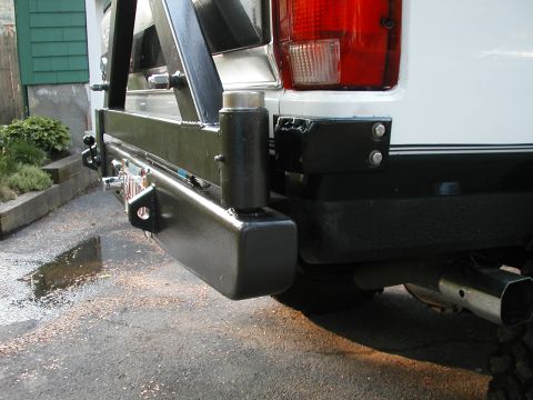 1994 Ford Bronco - Rear view of a white 1994 Ford Bronco, a black aftermarket bumper with a spare tire carrier and tow hitch.