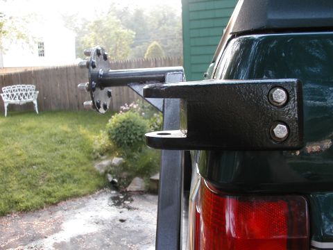 1994 Ford Bronco - Rear view of a dark green SUV's bumper mount and spare tire carrier, with a red taillight visible.
