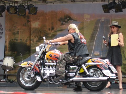 1992 Ford Crown Victoria - A man sits on a custom motorcycle with a flame paint job, presented on a stage.