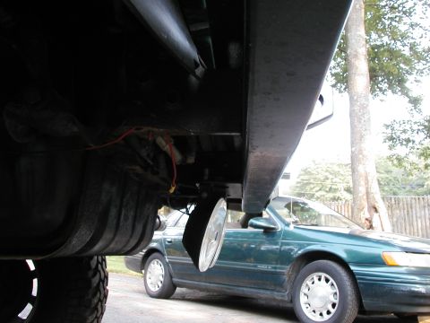 1994 Ford Bronco - Spare tire visible beneath a vehicle, with another car parked nearby.