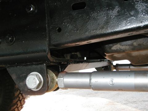 1994 Ford Bronco - Undercarriage view of a vehicle's frame and suspension components, showing a silver linkage and a large bolt.
