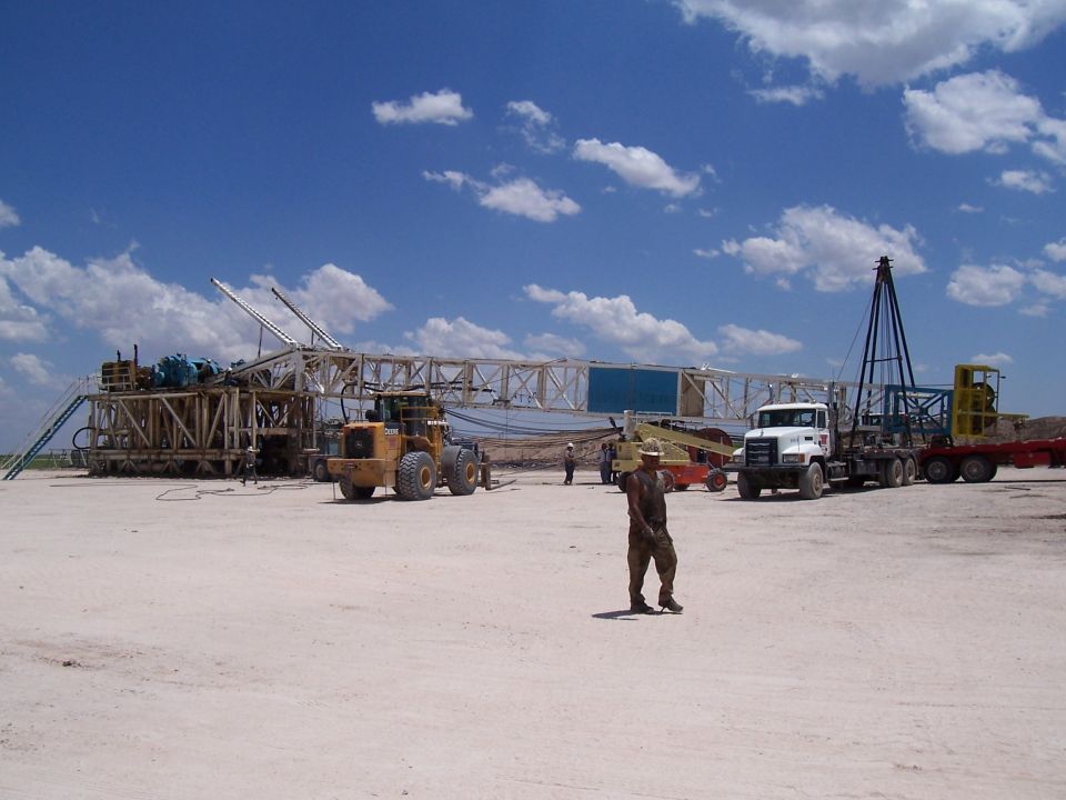 Oil rig equipment with a front loader and a truck under a blue sky