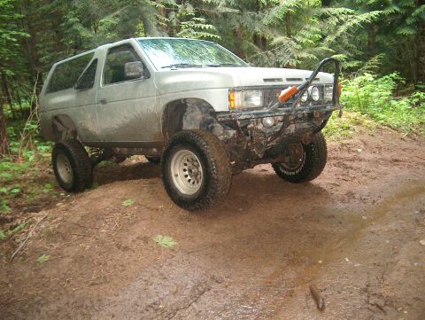 1995 Ford F-150 - Modified 1990s Nissan Pathfinder SUV navigating an off-road trail in a wooded area.