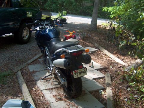 2002 Suzuki TL1000R - A dark blue motorcycle is parked on a path next to a green truck.