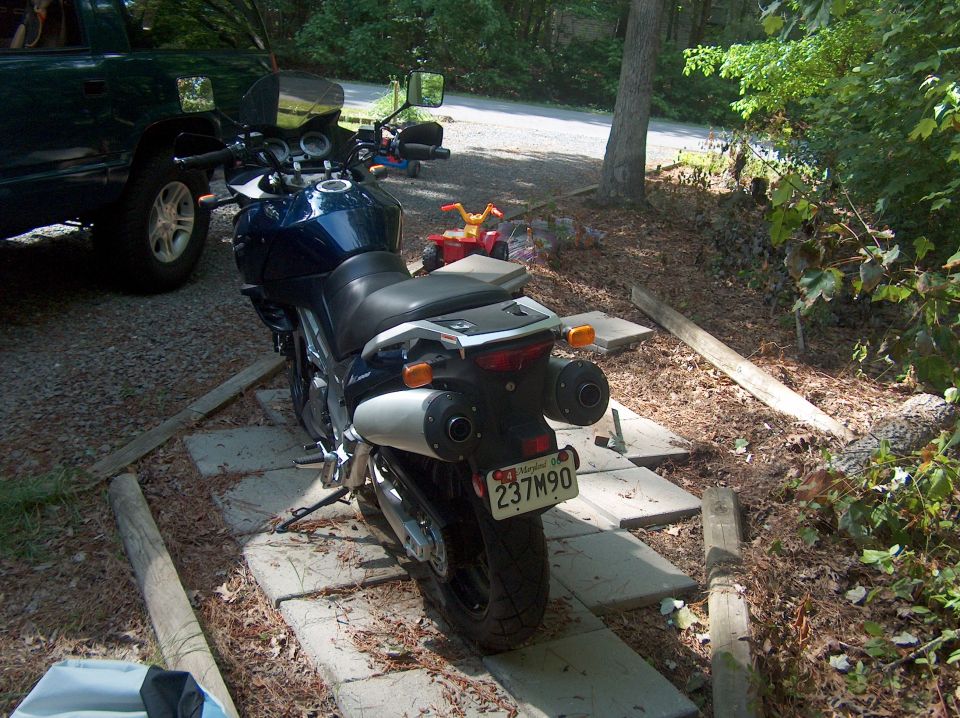 Dark blue motorcycle with dual exhaust pipes and a license plate reading 237M90