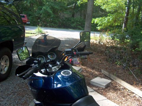 2002 Suzuki TL1000R - A blue motorcycle is parked next to a dark SUV in a wooded area.