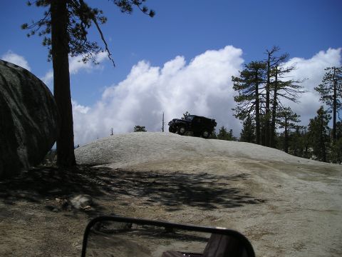 1989 Ford Bronco - SUV on a rocky mountain trail under a cloudy sky.